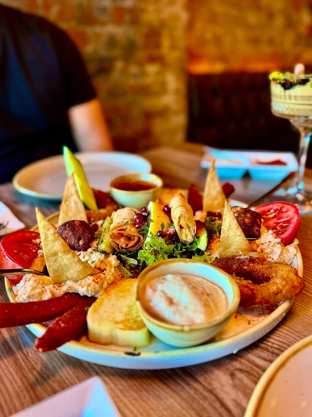 The mixed hot mezze board at Antep Kitchen Oxford from the side, with sigara böreği standing upright, sucuk, halloumi, calamari and two dipping sauces
