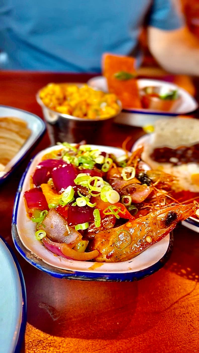 Devilled prawns at The Coconut Tree Oxford: king prawns in a sticky red sauce with red onion, mixed peppers and spring onion, with the Sri Lankan sweetcorn and parotta rotti behind