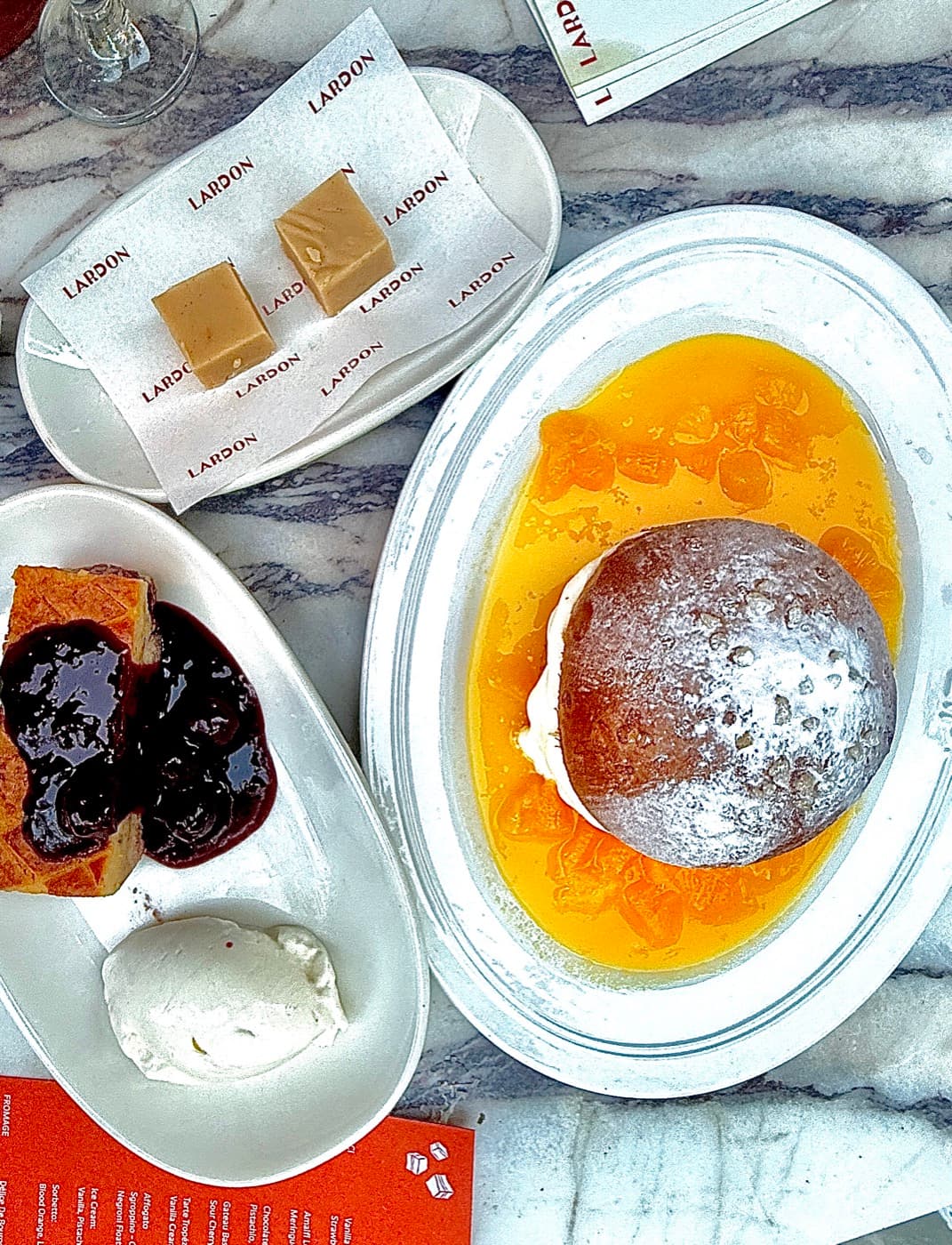 Overhead of desserts: tarte tropezienne, gateau basque with sour cherry, and Nonna's fudge