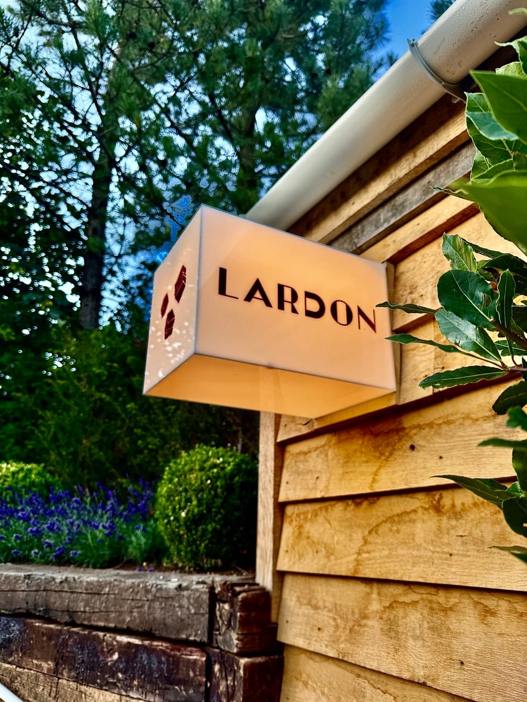 The illuminated Lardon sign on the timber building