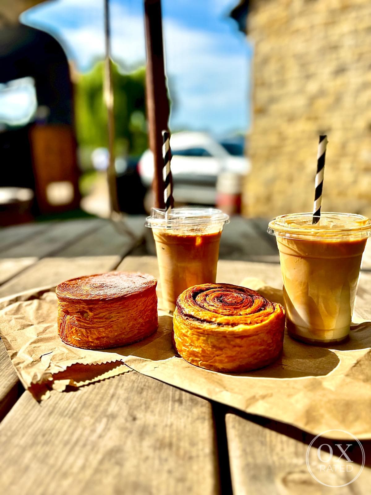 Iced coffees and pastries on a wooden picnic table