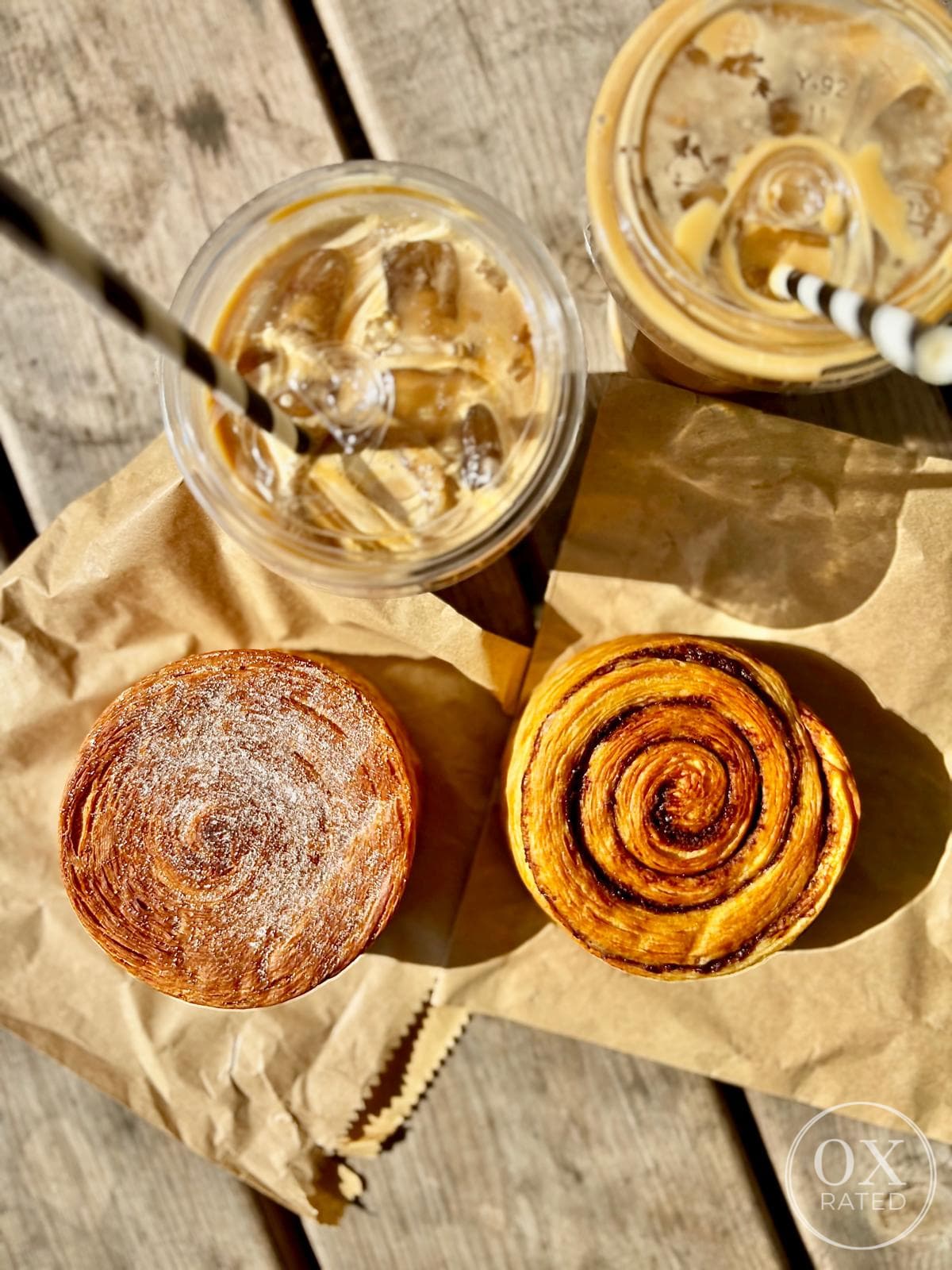 Overhead of two iced coffees, a cruffin and a cinnamon bun