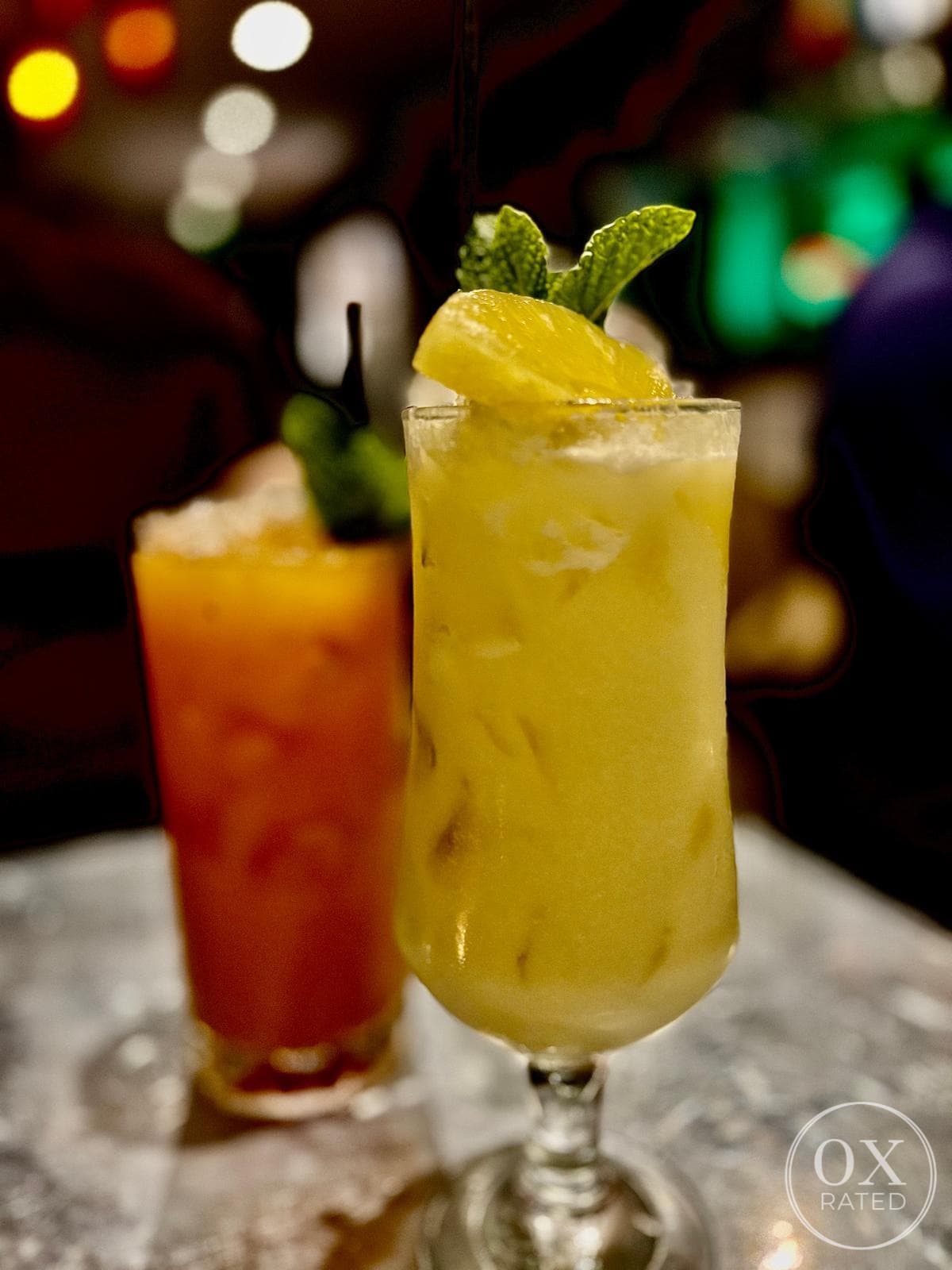 Two cocktails, one garnished with mint and a lemon slice